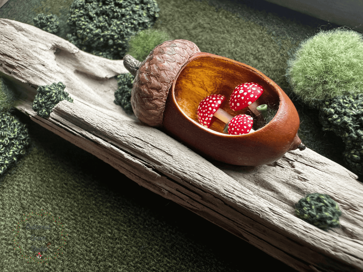 One-of-a-kind 5 x 7 original woodland artwork featuring hand-dyed New Hampshire wool (forest green in color), driftwood, embroidered moss, and a hand-carved acorn containing a tiny miniature forest scene with red fly agaric mushrooms, lichen, and moss, displayed in a handmade salvaged barn wood frame (grey in color).