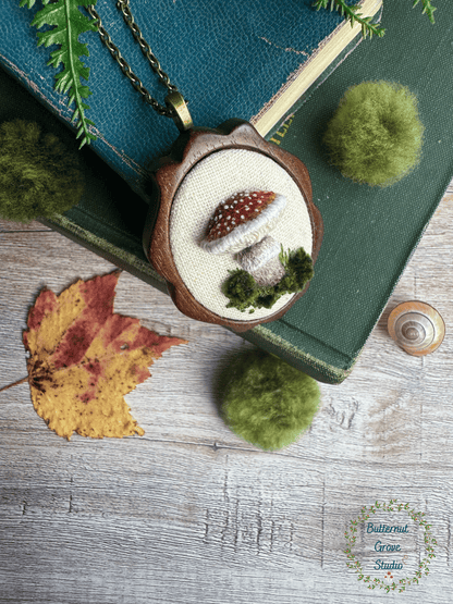 A tiny treasure from the forest floor, stitched by hand. Nestled inside a hand-carved walnut frame, this piece is small enough to wear as a pendant, or to add a bit of magic to your wall as a miniature work of art.  

Dimensions: 1.5" wide × 2" tall
Materials: Hand-stitched embroidery, hand-carved walnut frame

Choose how you would like to enjoy your little woodland treasure:

Please leave a note at checkout with your preference:

• Hand-painted mushroom picture hanger 
• 18" bronze chain with lobster clasp