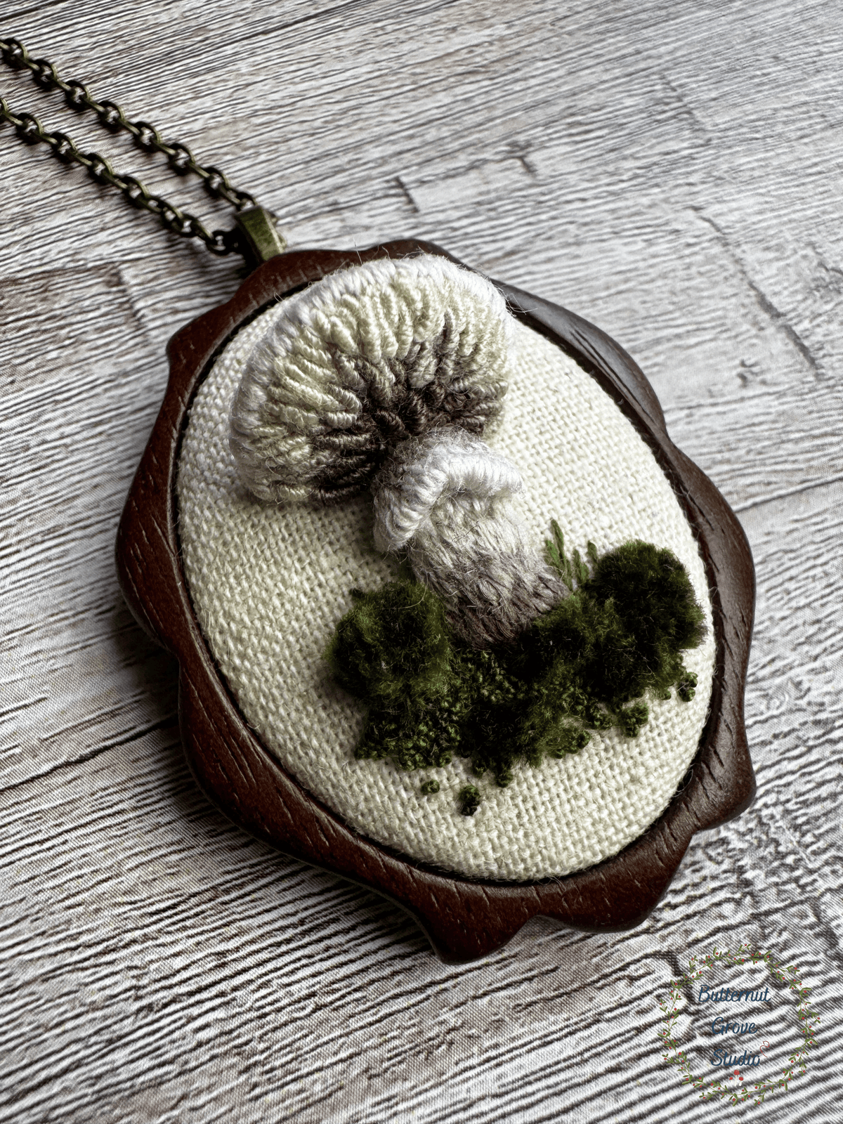 A tiny treasure from the forest floor, stitched by hand. Nestled inside a hand-carved walnut frame, this piece is small enough to wear as a pendant, or to add a bit of magic to your wall as a miniature work of art.  

Dimensions: 1.5" wide × 2" tall
Materials: Hand-stitched embroidery, hand-carved walnut frame

Choose how you would like to enjoy your little woodland treasure:

Please leave a note at checkout with your preference:

• Hand-painted mushroom picture hanger 
• 18" bronze chain with lobster clasp
