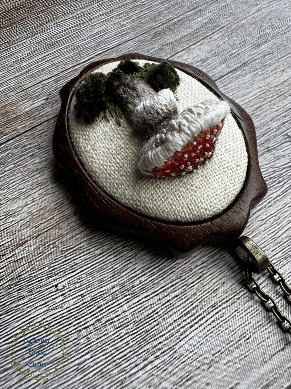 A tiny treasure from the forest floor, stitched by hand. Nestled inside a hand-carved walnut frame, this piece is small enough to wear as a pendant, or to add a bit of magic to your wall as a miniature work of art.  

Dimensions: 1.5" wide × 2" tall
Materials: Hand-stitched embroidery, hand-carved walnut frame

Choose how you would like to enjoy your little woodland treasure:

Please leave a note at checkout with your preference:

• Hand-painted mushroom picture hanger 
• 18" bronze chain with lobster clasp
