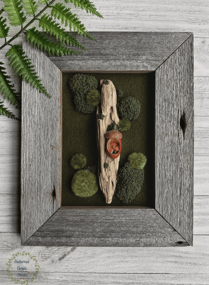 One-of-a-kind 5 x 7 original woodland artwork featuring hand-dyed New Hampshire wool (forest green in color), driftwood, embroidered moss, and a hand-carved acorn containing a tiny miniature forest scene with red fly agaric mushrooms, lichen, and moss, displayed in a handmade salvaged barn wood frame (grey in color).