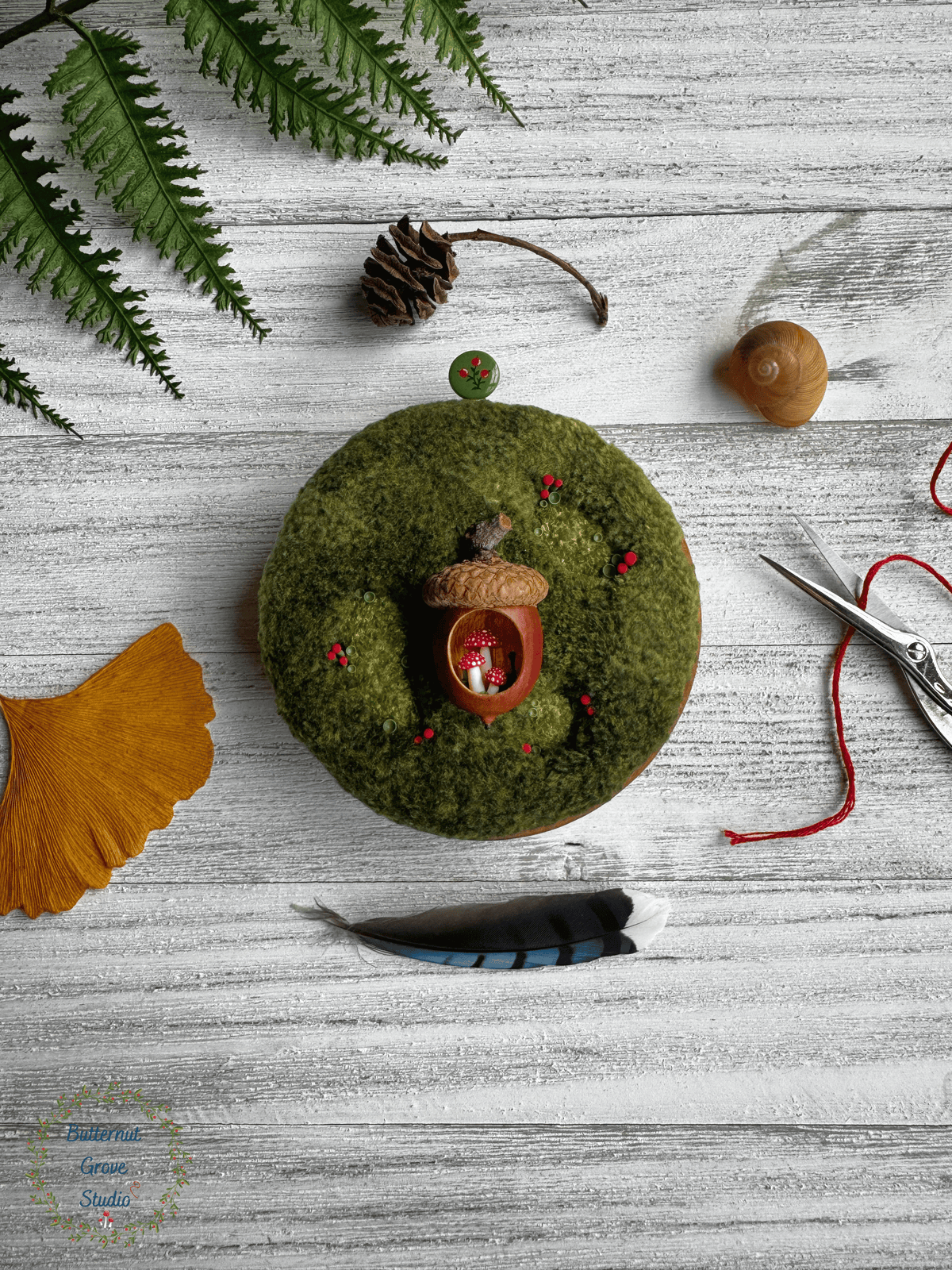 One-of-a-kind 3-inch micro-embroidery featuring a hand-carved acorn surrounded by embroidered moss, British soldier and fairy cup lichens, and tiny woodland details, framed in warm handmade cherry wood frame.