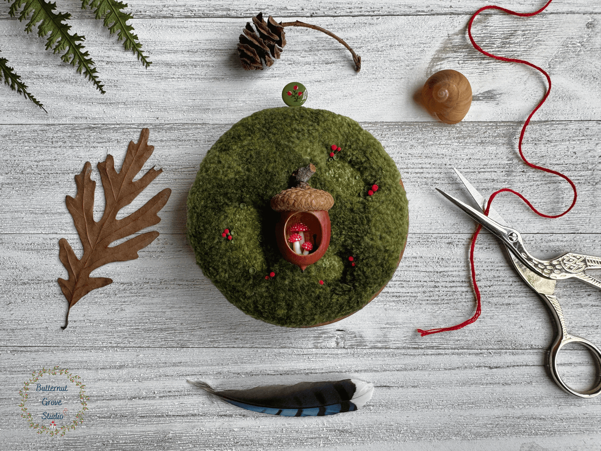 One-of-a-kind 3-inch micro-embroidery featuring a hand-carved acorn surrounded by embroidered moss, British soldier and fairy cup lichens, and tiny woodland details, framed in warm handmade cherry wood frame.