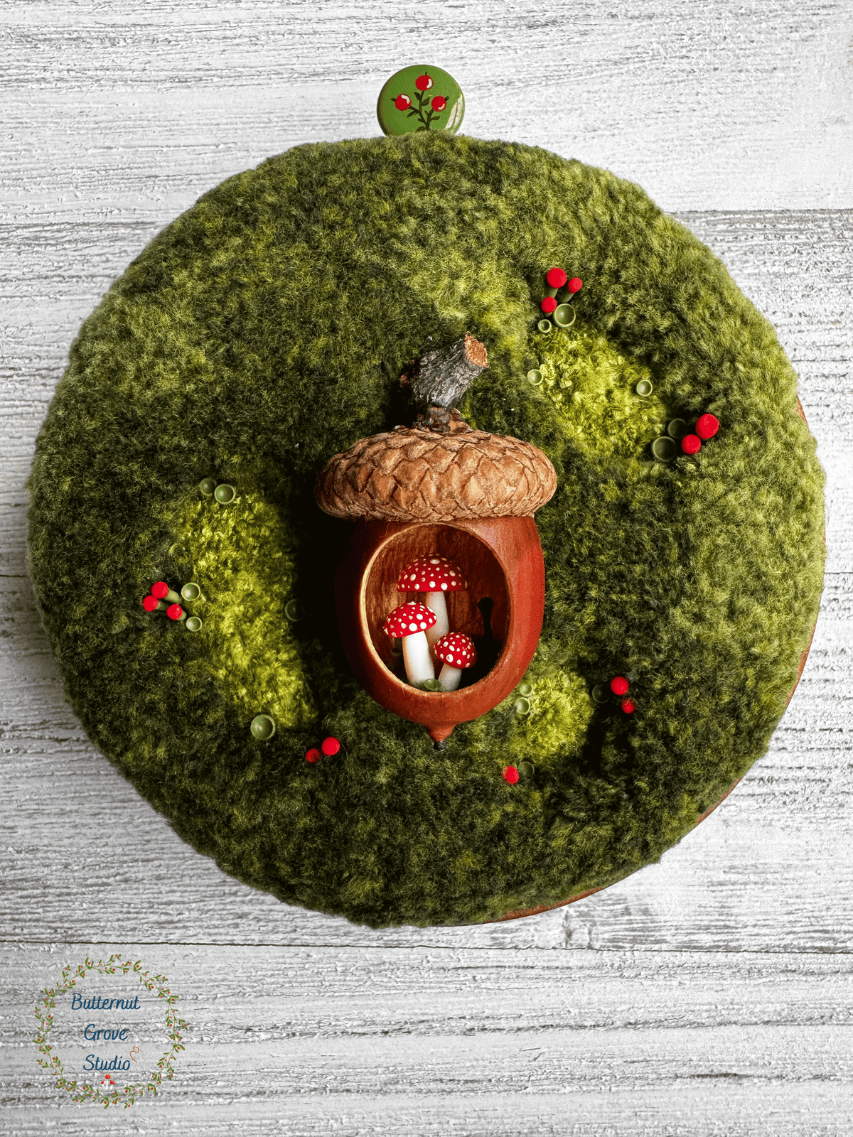 One-of-a-kind 3-inch micro-embroidery featuring a hand-carved acorn surrounded by embroidered moss, British soldier and fairy cup lichens, and tiny woodland details, framed in warm handmade cherry wood frame.
