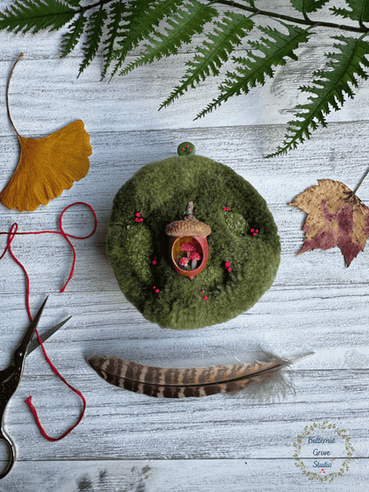 One-of-a-kind 3-inch micro-embroidery featuring a hand-carved acorn surrounded by embroidered moss, British soldier and fairy cup lichens, and tiny woodland details, framed in warm handmade walnut wood frame.