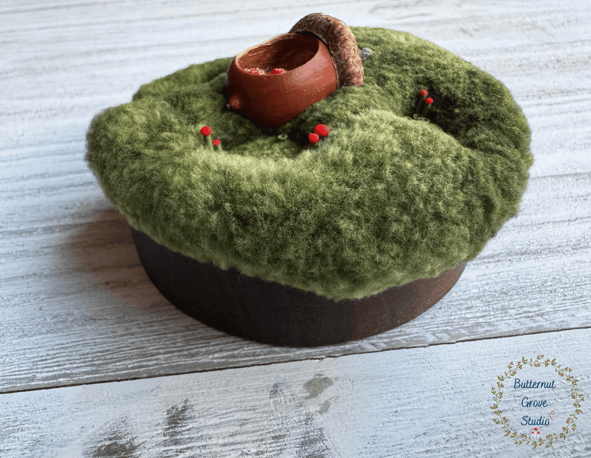 One-of-a-kind 3-inch micro-embroidery featuring a hand-carved acorn surrounded by embroidered moss, British soldier and fairy cup lichens, and tiny woodland details, framed in warm handmade walnut wood frame.