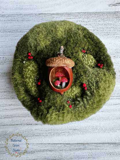One-of-a-kind 3-inch micro-embroidery featuring a hand-carved acorn surrounded by embroidered moss, British soldier and fairy cup lichens, and tiny woodland details, framed in warm handmade walnut wood frame.